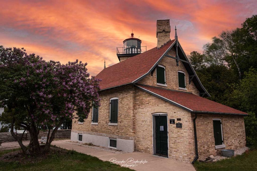 Door County’s Eagle Bluff Lighthouse: Scenic Views, History, and Things to Do Nearby 1 Eagle Bluff Lighthouse in Door County glowing under a pink sunset sky, with a lilac tree in bloom
